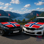 Fanshoppen Norge car accessory pack with Norwegian flags on hood, side mirrors, and roof. Black car driving on a scenic road.
